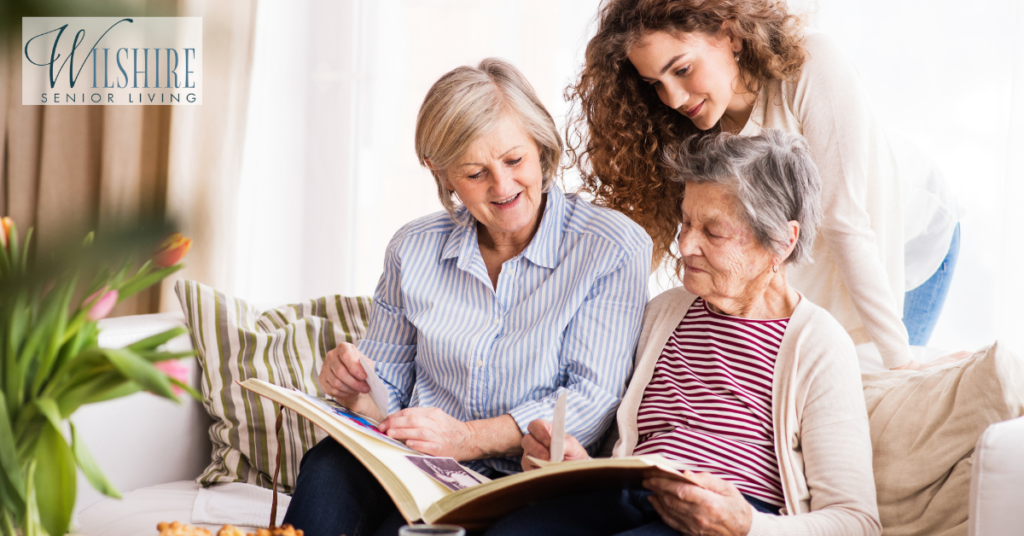 A teenage girl, her mother and grandmother looking at old photographs. Family and generations concept. Visiting a loved one in memory care.