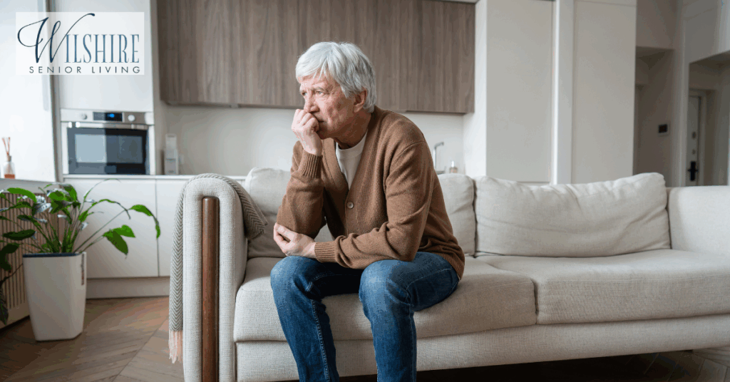 An elderly man sitting alone on a sofa, appearing deep in thought — representing the challenges and emotions of Alzheimer’s care at home.